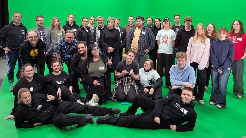 Virtuaalistudiokurssin tekijät ryhmäkuvassa vihreän kuvaustaustan edessä.